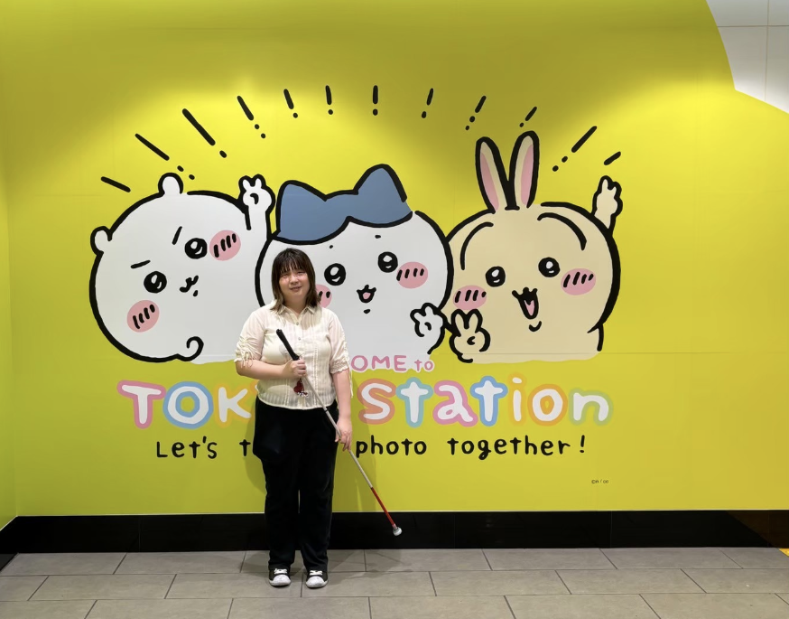 ちいかわらんどのちいかわのキャラクターが描かれた壁の前に立つ昌美さんの写真