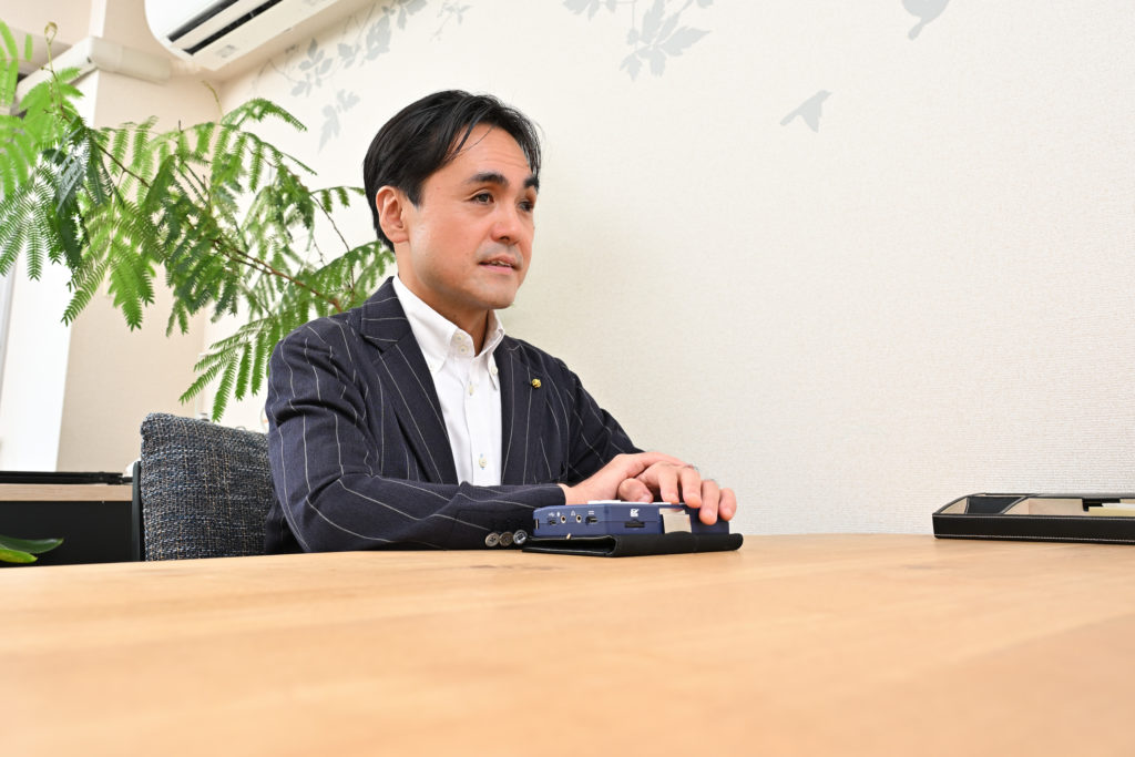 テーブルに手を乗せて語る大胡田さん