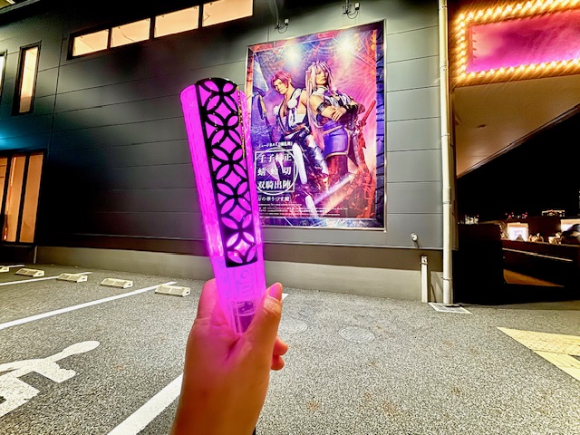 刀剣乱舞のポスターの前に紫のペンライトを差し出した写真